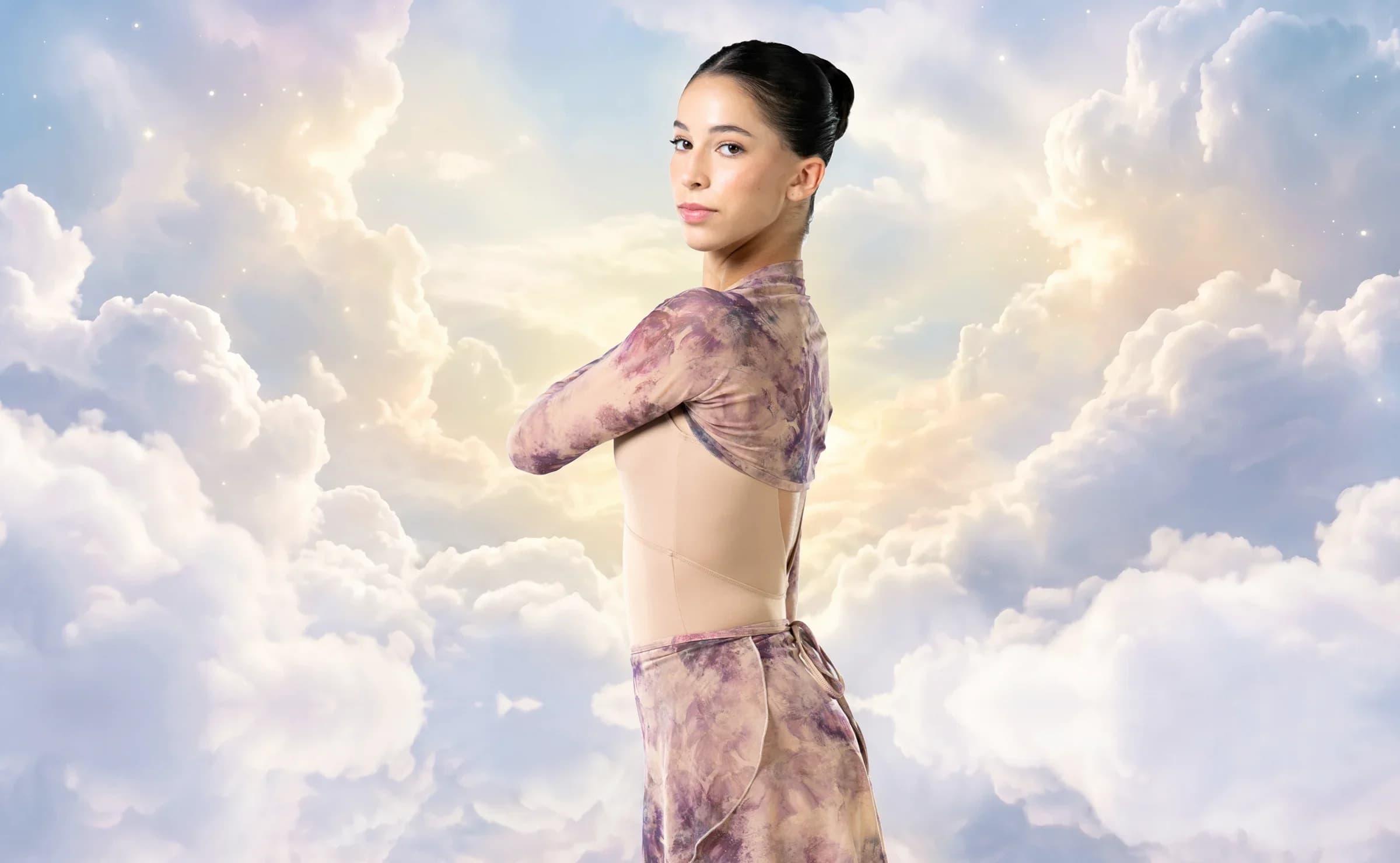 Dancer in a floral leotard posed among soft clouds